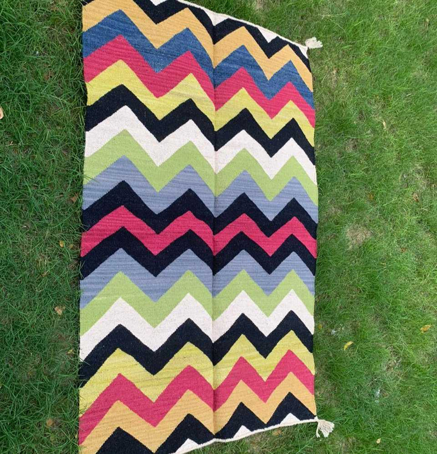 Multi Chevron Dhurrie Rug with mix colors and patterns on grass